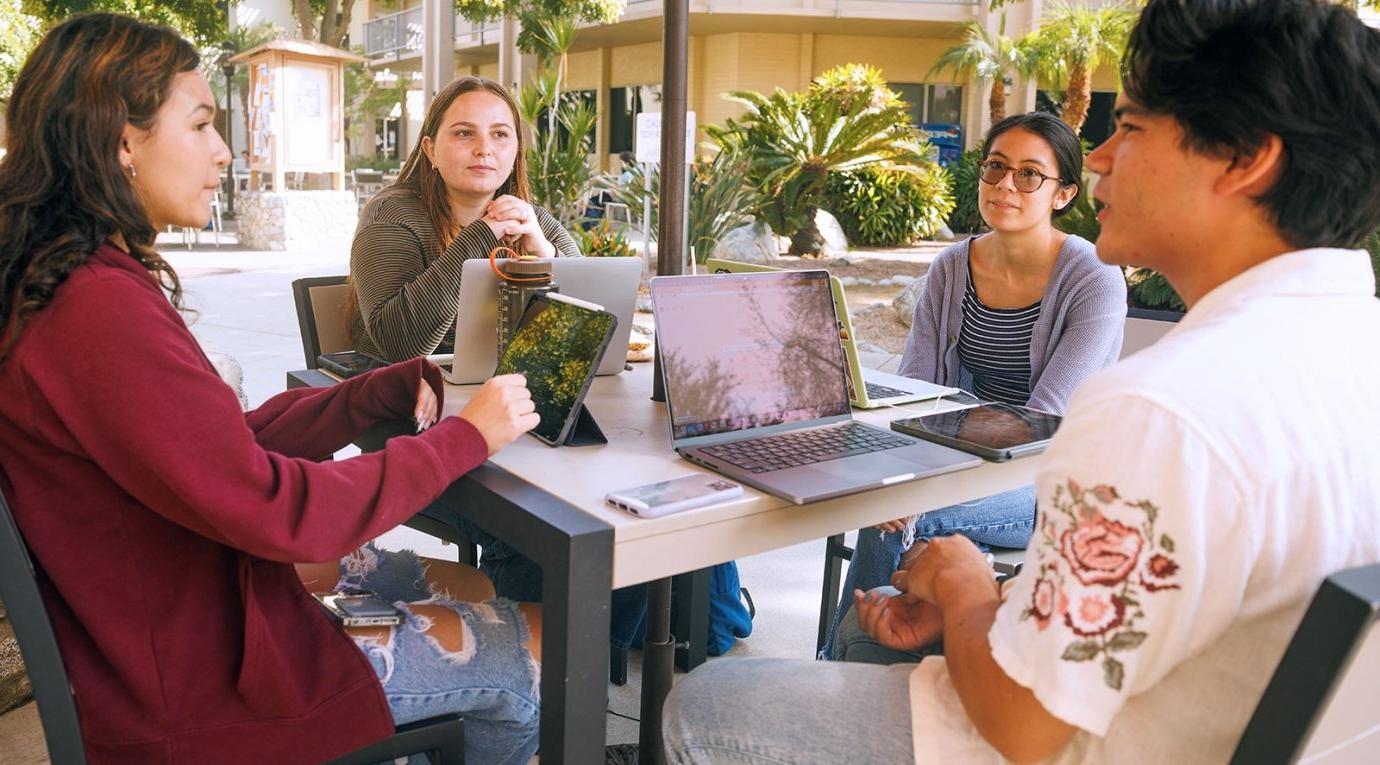 four students sit at a table and converse