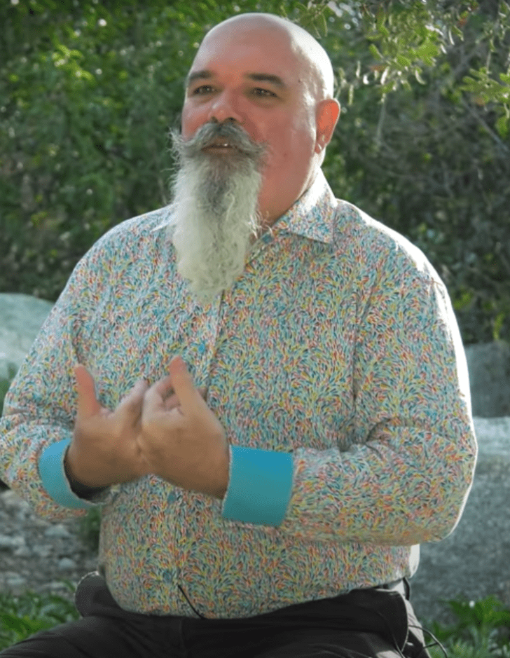 a still from a video showing brian keely sitting outside surrounded by native california plants